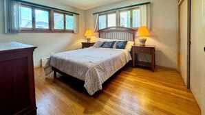 A bedroom with a bed, two bedside tables with lamps, a ceiling fan, and windows with curtains. - Spacious Single Family House with Parking (Chicago)