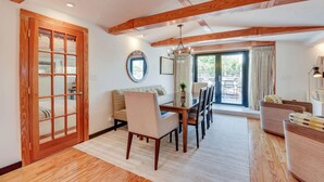 A spacious living area with a wooden ceiling, a dining table with chairs, a sofa, and a large window with curtains. - Slack Tide On Duval Street (Key West)