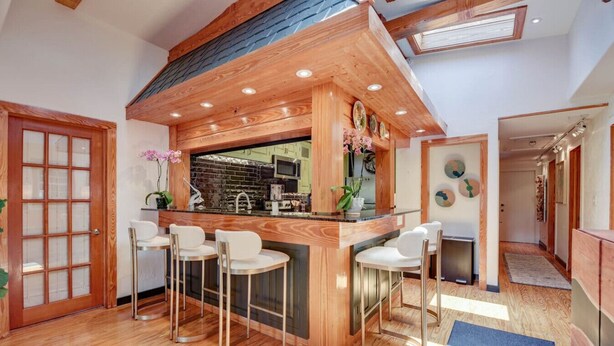 A modern kitchen with a wooden bar, three bar stools, and a large window. - Slack Tide On Duval Street (Key West)
