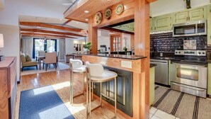 A modern kitchen with wooden beams, a central island with bar stools, and stainless steel appliances. - Slack Tide On Duval Street (Key West)