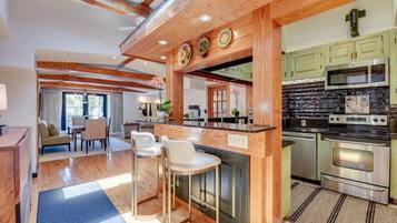 A modern kitchen with wooden beams, a central island with bar stools, and stainless steel appliances.