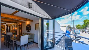 A modern interior with a dining area, a sofa, and a balcony with a view of the street. - Slack Tide On Duval Street (Key West)