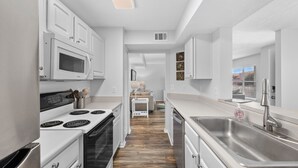 Une cuisine moderne avec des meubles blancs, des appareils en acier inoxydable et un plancher en bois.