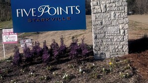 Ein Schild für Five Points in Starkville, mit einer Steinsäule und einem hölzernen Balken darüber.