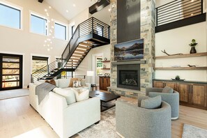 A spacious living area with a staircase, a fireplace, and a view of the outdoors.
