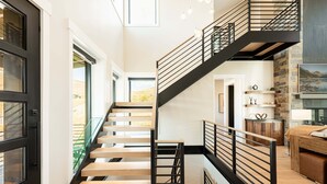 A modern staircase with wooden steps and black railings, leading to a second floor. - Five-Star Base for Powder Runs & Lake Days - Adventure Elevated (Heber City)