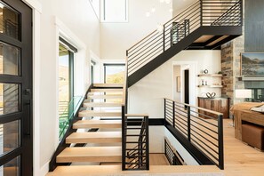 A modern staircase with wooden steps and black railings, leading to a second floor.