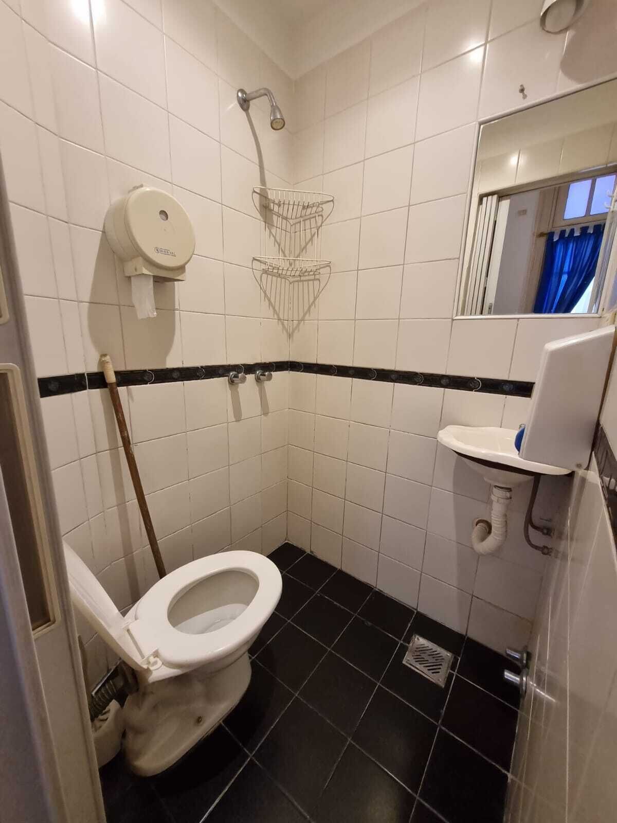 Un baño pequeño con azulejos, que incluye inodoro, ducha y lavamanos.