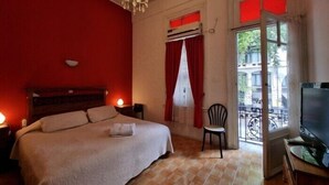 Une chambre à coucher avec un lit, une chaise, une télévision et un balcon offrant une vue.