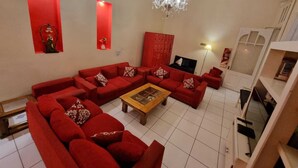 Un salon avec des canapés rouges, une table basse en bois et un lustre.