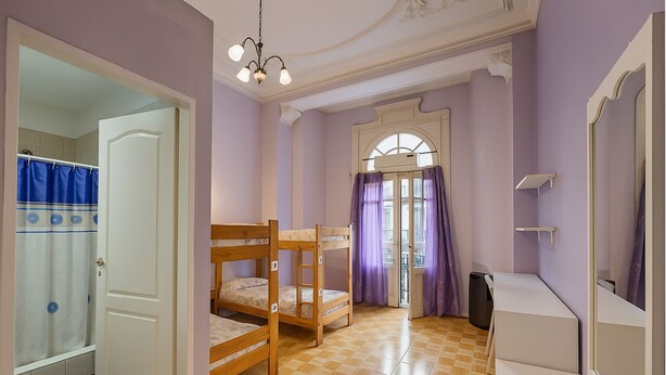 Une chambre avec des lits superposés, un petit bureau, un miroir et une porte donnant sur une salle de bain.