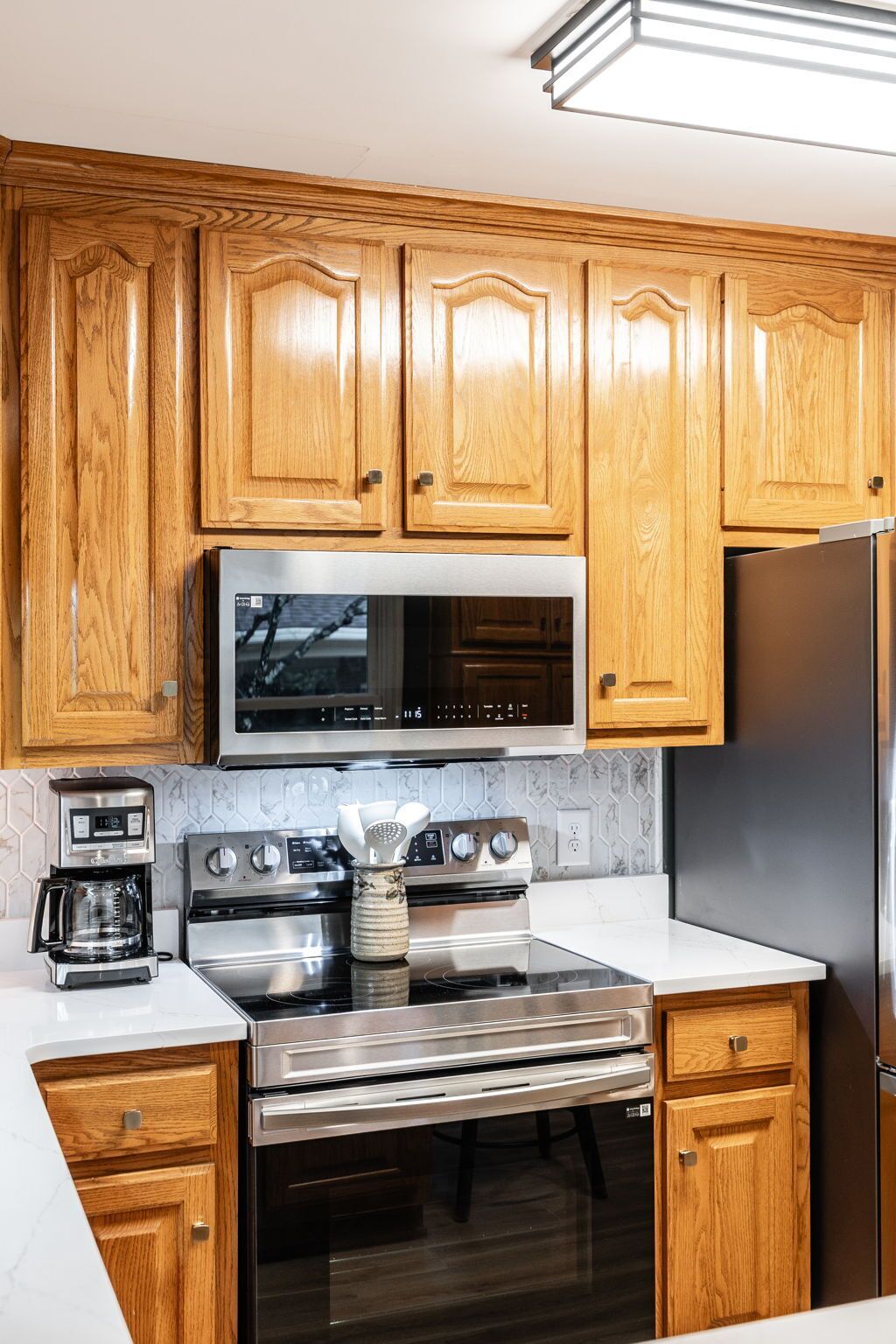 A kitchen with wooden cabinets, a stainless steel microwave, a double oven, and a refrigerator.