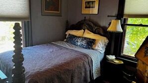 A bedroom with a bed, a nightstand, a lamp, and two framed pictures on the wall.