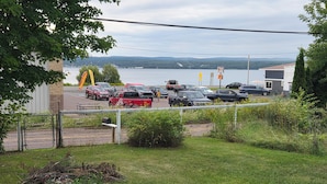 A parking lot with several vehicles, a body of water, and a building in the background.