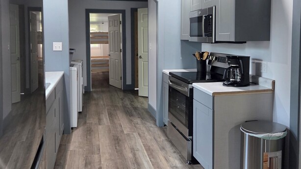 A modern kitchen with grey cabinets, a stainless steel refrigerator, a microwave, and a coffee maker.