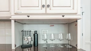 A kitchen with white cabinets, a granite countertop, and a stainless steel kettle. - Putting Green - Life Sized Chess -Luxury Aesthetic (Greensboro)