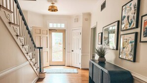 A hallway with a wooden floor, a blue bench, and a door leading outside. - Putting Green - Life Sized Chess -Luxury Aesthetic (Greensboro)