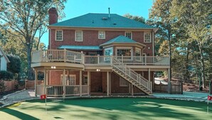 A two-story house with a balcony and a backyard with a putting green. - Putting Green - Life Sized Chess -Luxury Aesthetic (Greensboro)