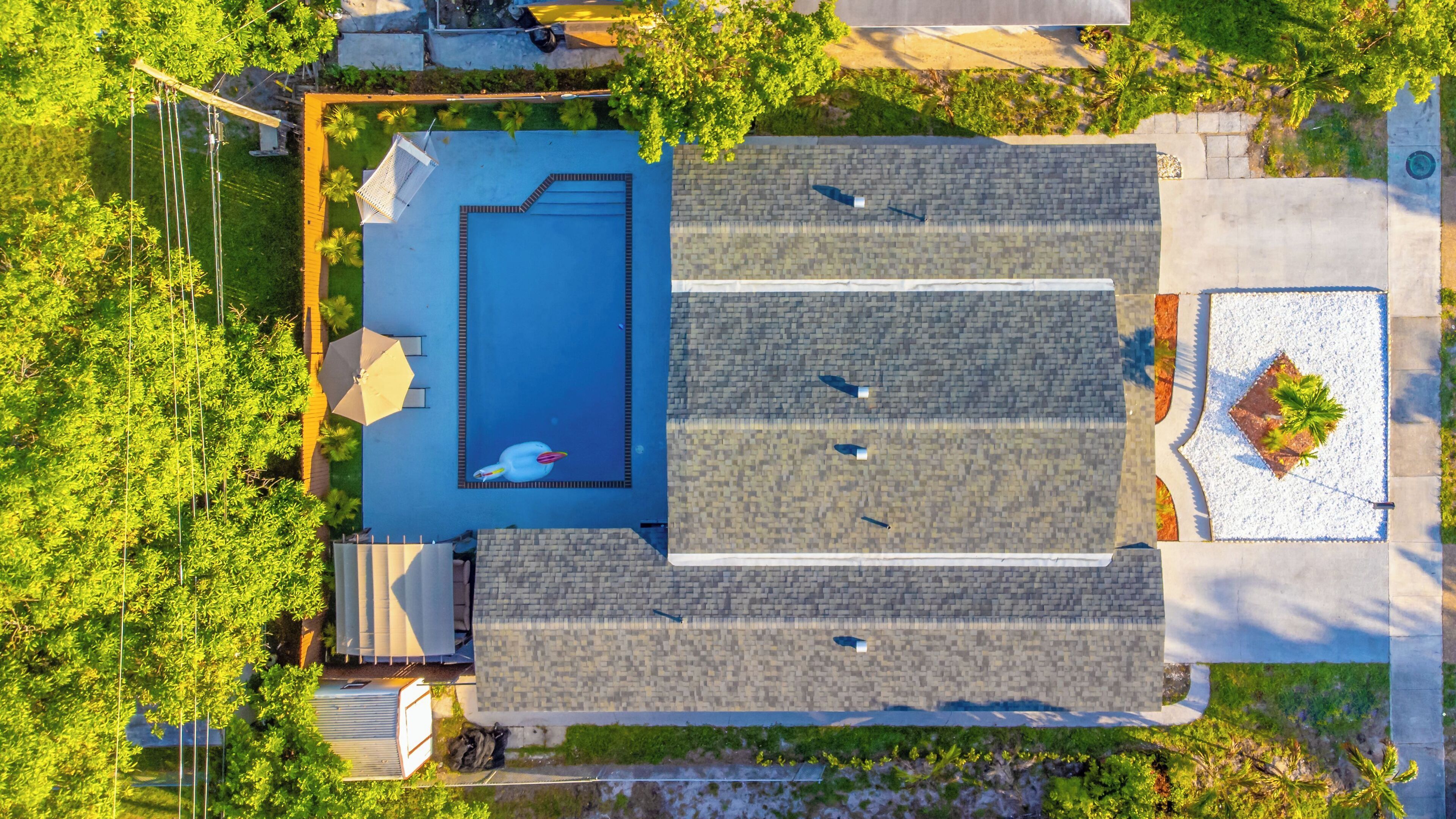 Vue aérienne d’une propriété résidentielle dotée d’une piscine, d’un patio couvert et d’un jardin.
