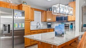 A modern kitchen with wooden cabinets, stainless steel appliances, a granite countertop, and a 'Welcome' sign. - Surf Shack | Water Park | Ocean Lakes (Horry County)