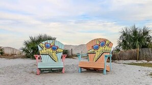 Two colorful Adirondack chairs on a sandy beach with palm trees in the background. - Surf Shack | Water Park | Ocean Lakes (Horry County)