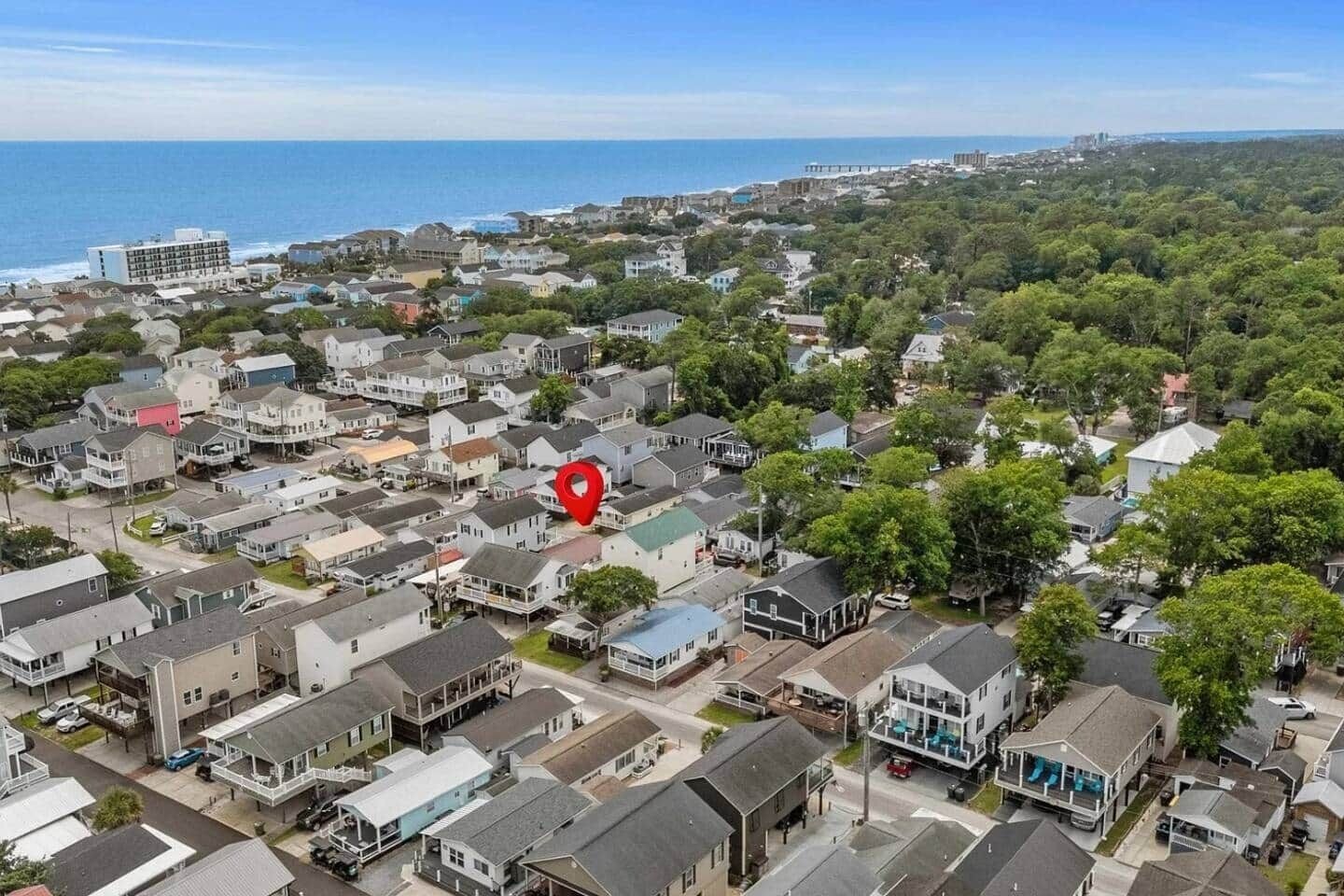 Ett bostadsområde med hus, en röd markör som visar platsen och utsikt över havet.