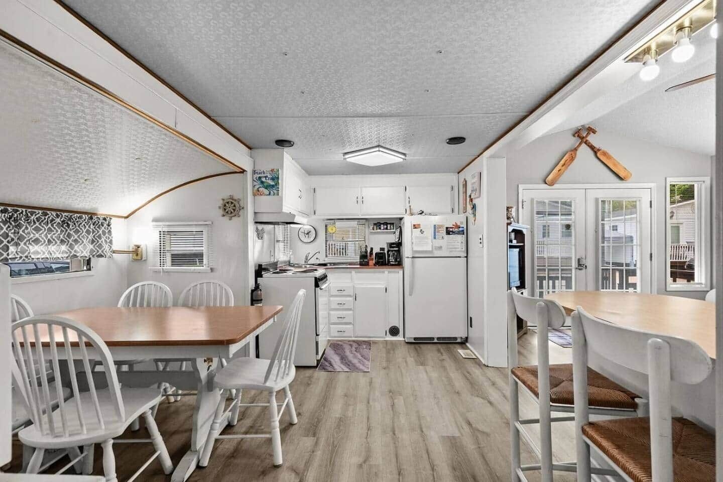 Une cuisine de taille réduite avec des meubles blancs, une table à manger en bois et un comptoir pour prendre le petit-déjeuner.