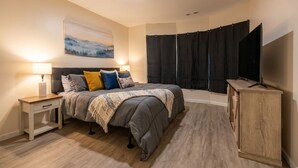 A bedroom with a bed, bedside tables, a TV cabinet, and a painting on the wall. - 6-Bedroom 3-Bath Spacious Retreat 5 min to Downtown Indy Big Fenced-In Backyard (Indianapolis)