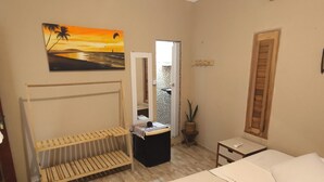 Ein Schlafzimmer mit Bett, einer Bank, einem kleinen Tisch, einem Spiegel und einem Bild an der Wand.