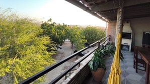 Ein Balkon mit Blick auf eine üppige, grüne Landschaft, einer Hängematte und einem Backofen aus Ziegelsteinen.