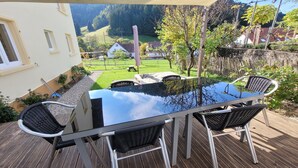 A deck with a glass-top table and four black wicker chairs. - Cozy and stylish family-friendly vacation apartment in the middle of Simonswald (Simonswald)
