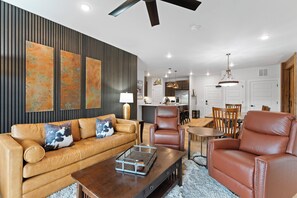 A modern living room with a leather sofa, a wooden coffee table, and a dining area with a wooden table and chairs.