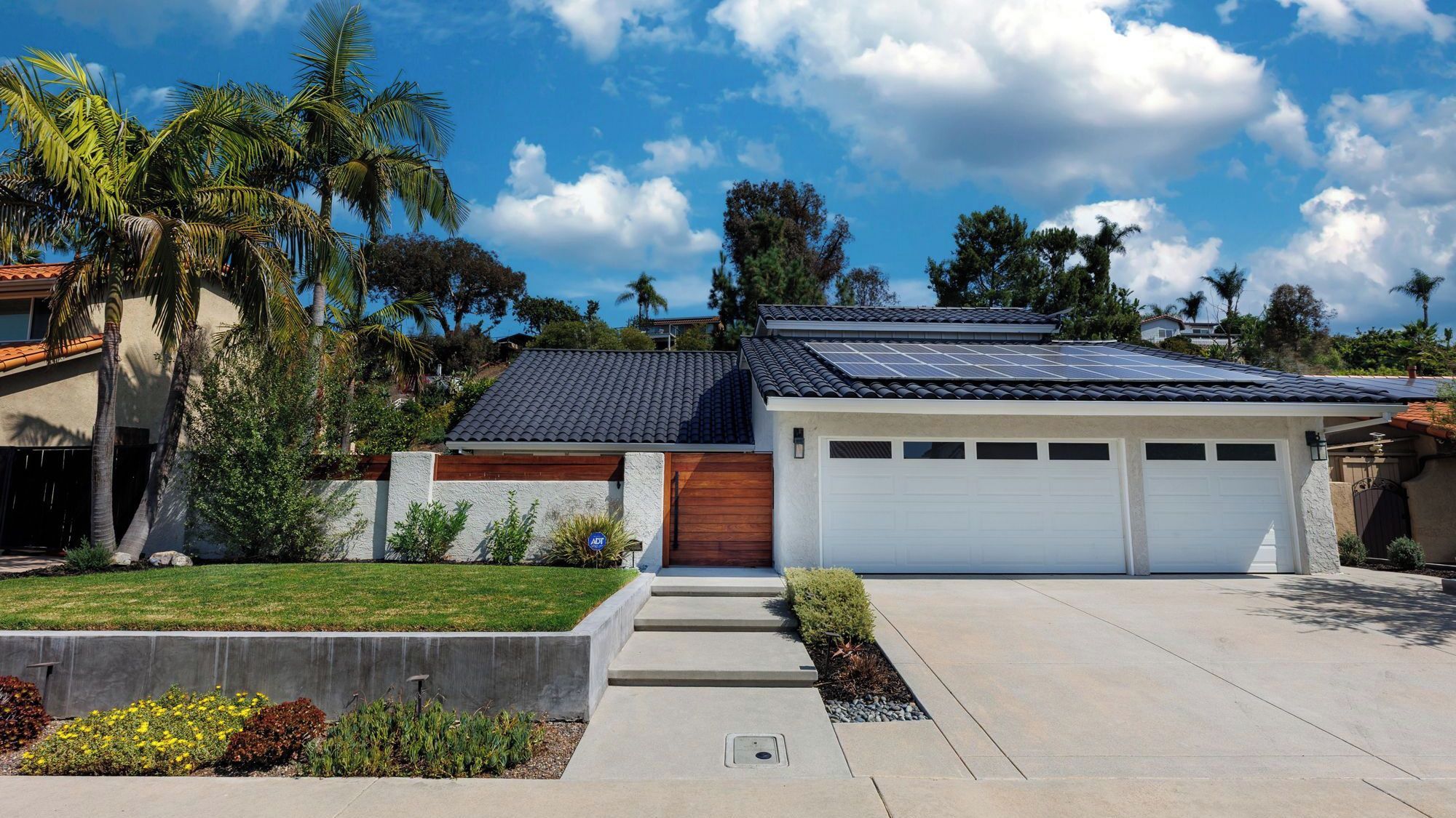 A modern house with a garage, solar panels, and a well-maintained lawn.
