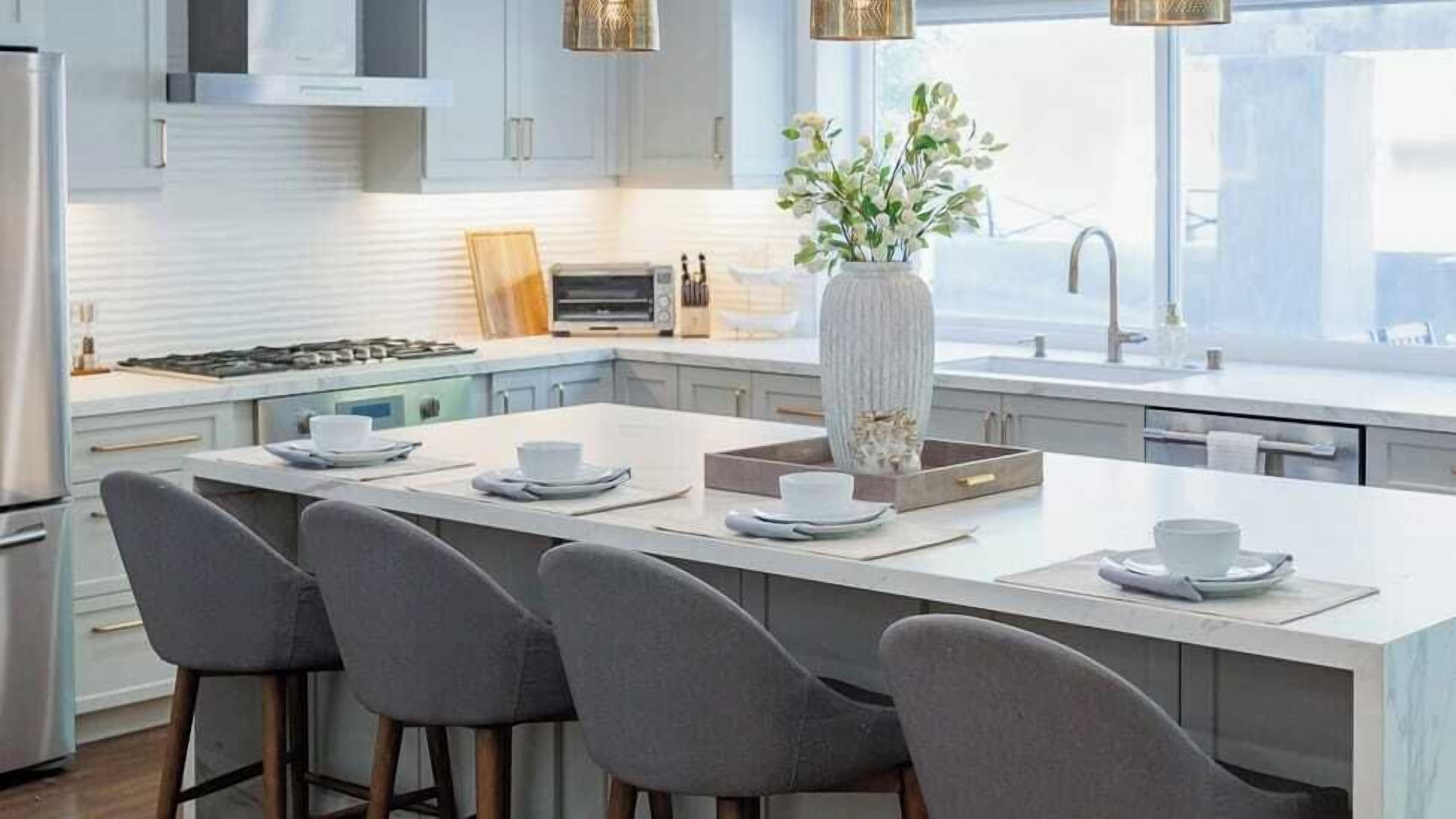 A modern kitchen with a central island, bar stools, a large vase, and a window providing natural light.