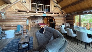 A log cabin interior with a loft bedroom, a billiards table, and a cozy seating area. - Ocean Front Property with Beach Access (Ketchikan)