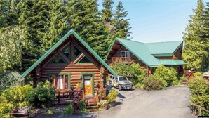 A log cabin with a green roof, surrounded by dense forest. - Ocean Front Property with Beach Access (Ketchikan)
