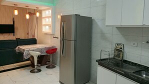 Une cuisine équipée d’un réfrigérateur en acier inoxydable, d’une table à manger recouverte d’une nappe à motifs floraux et d’un tabouret de bar.