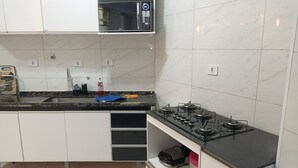 Une cuisine moderne avec des meubles blancs, un plan de travail noir et une cuisinière à gaz.