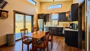 Una cocina moderna con armarios oscuros, una mesa de comedor de madera y vistas al exterior.