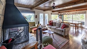 Una sala de estar acogedora con chimenea, techo de madera y ventanas amplias.