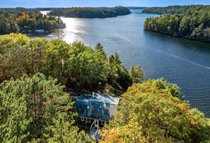 Un chalet au bord du lac, entouré d’une forêt dense, offrant une vue dégagée sur le lac et le rivage au loin.