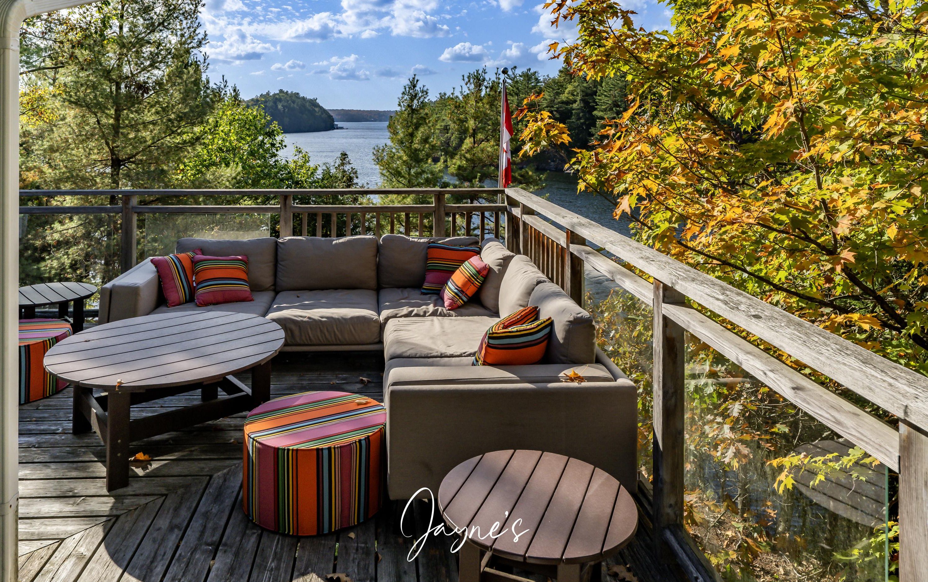 Een terras met een bank, twee ronde tafels en kleurrijke poefs.