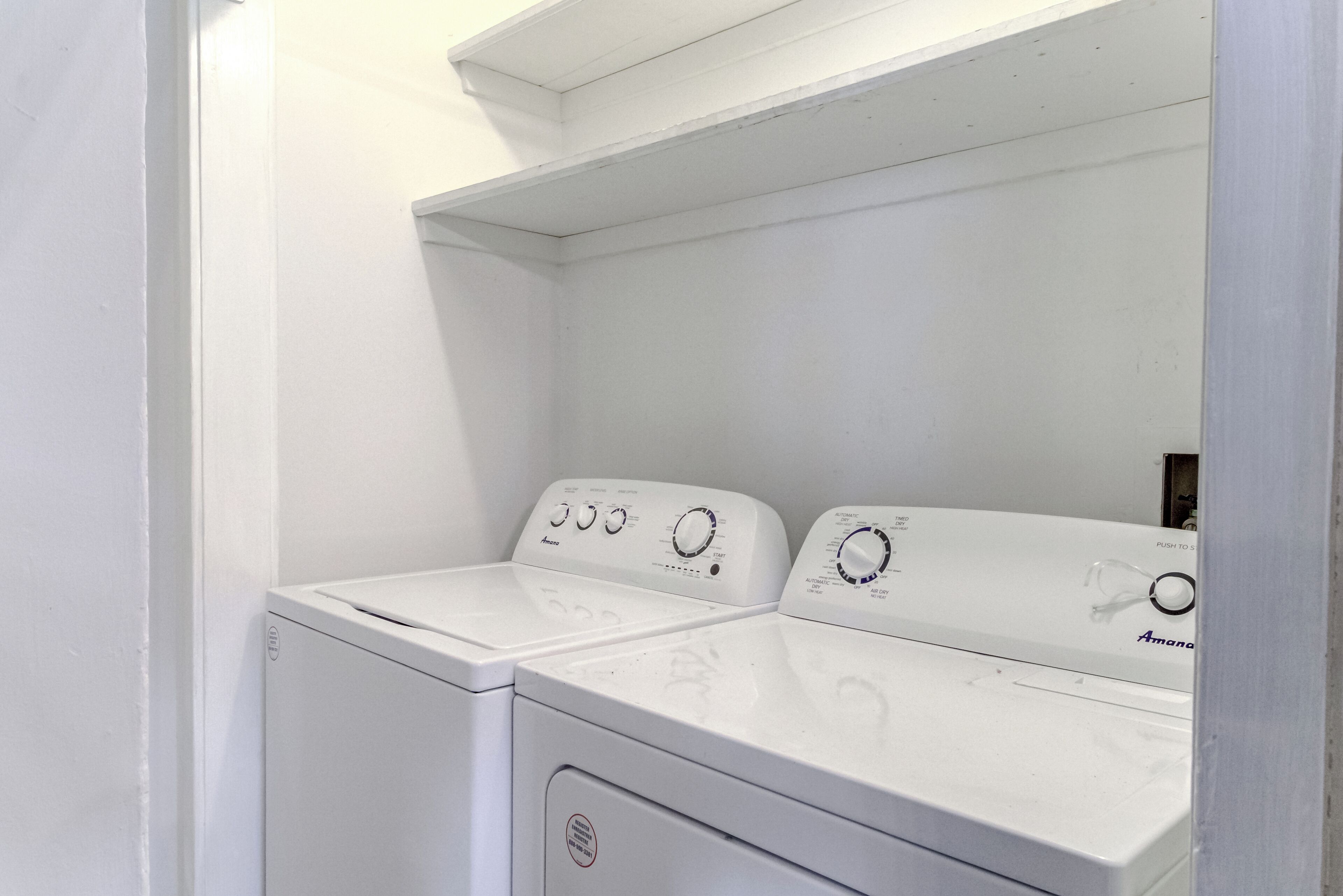 A white, two-door washer and dryer unit with control knobs and a brand label.