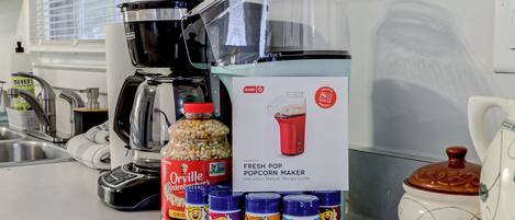 Een keukenblad met een nieuwe popcornmachine, een koffiezetapparaat en verschillende kruidenflesjes.