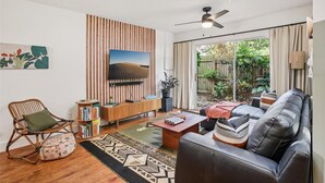 A modern living room with a TV, sofa, and a bookshelf. - Amazing cottage in sunny Tampa close to everything. (Tampa)