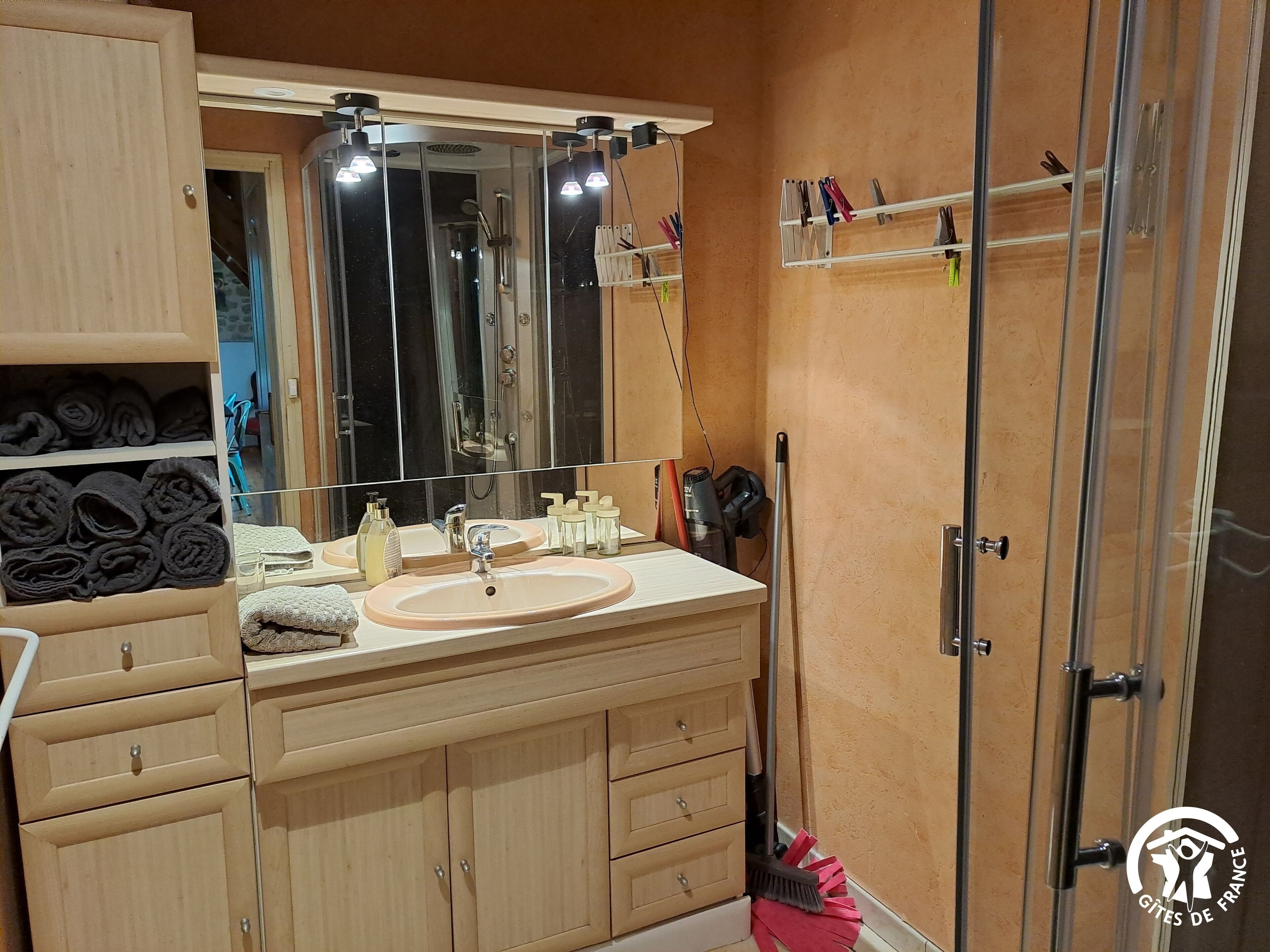 Ein Badezimmer mit Waschbecken, großem Spiegel, Dusche und Handtuchhalter.