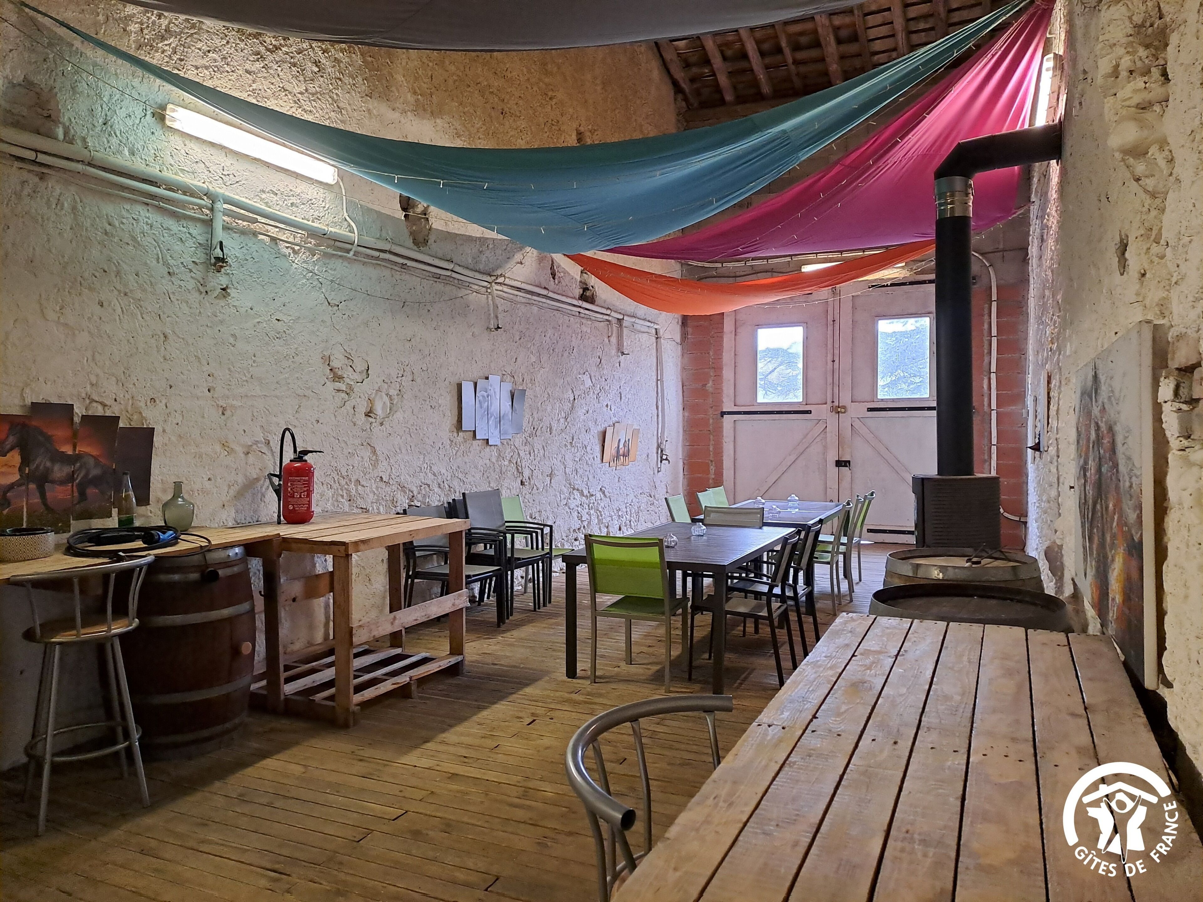 Une pièce rustique, avec des meubles en bois, une table, des chaises, un poêle à bois et un mur au style rustique.