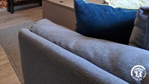 Een woonkamer met een televisie, een bank, een salontafel en een open haard.
