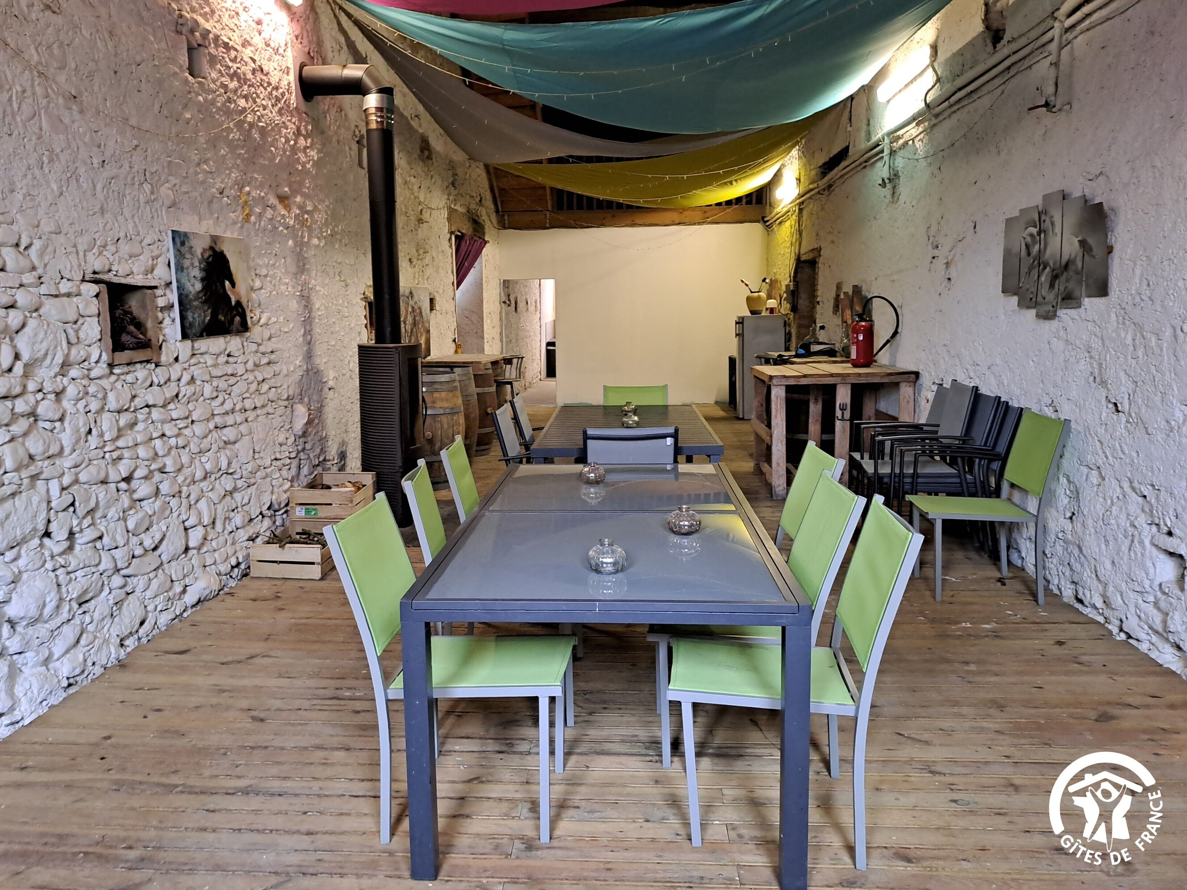 A rustic dining area with a stone wall, wooden floor, and a long table with chairs.