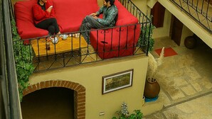 Ein mehrstöckiger Innenhof mit einem roten Sofa, einem Holztisch und Topfpflanzen.